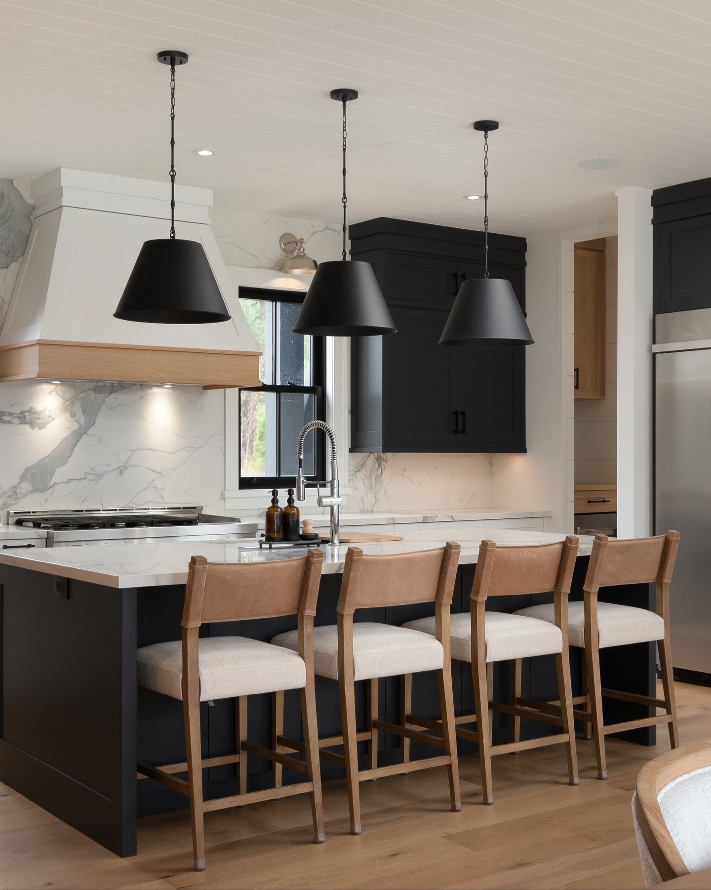 Bigwin Island cottage kitchen with black island, marble counter and white oak trimmed range hood by Bateman Fine Cabinetry