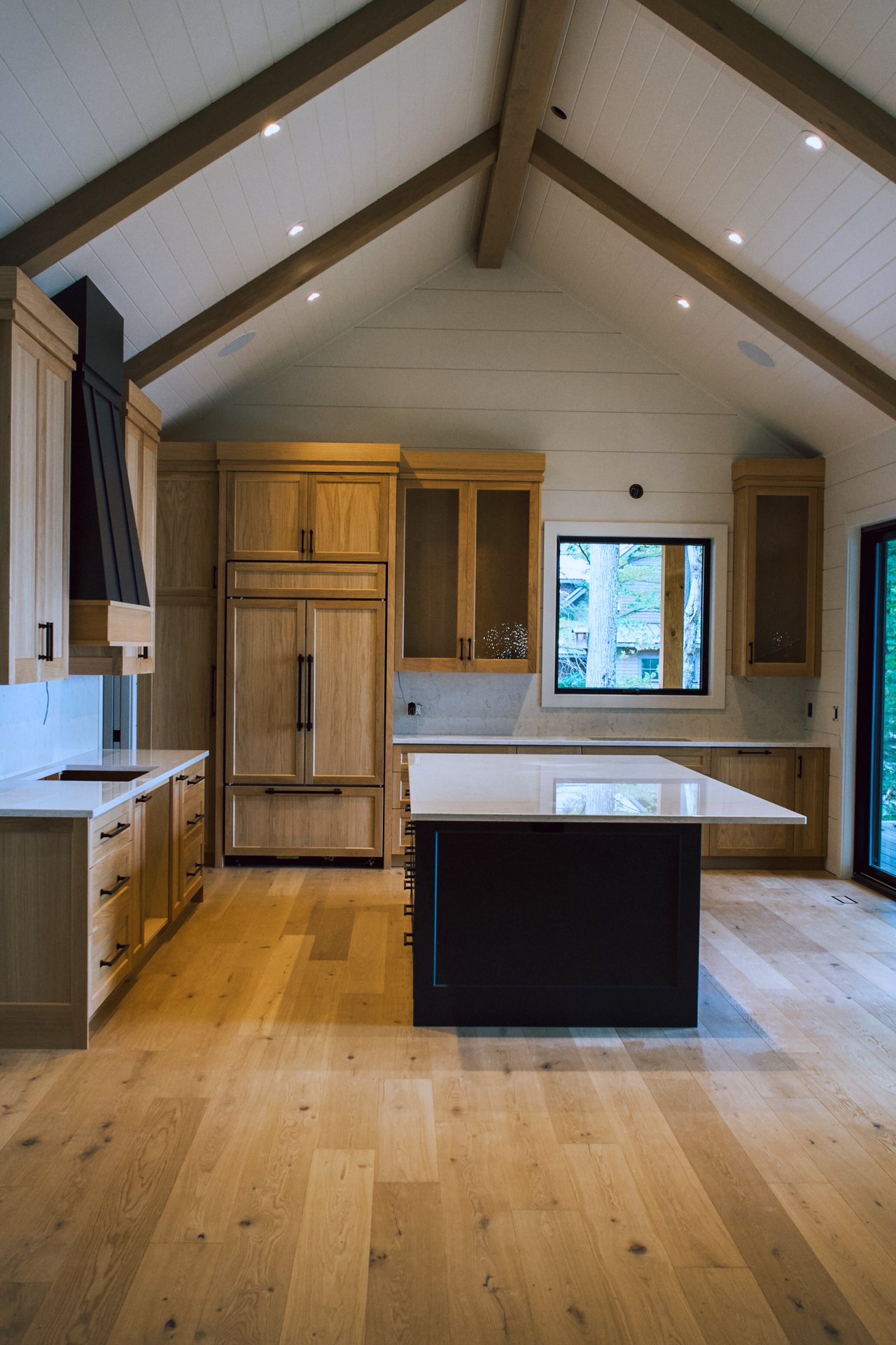 White oak cottage kitchen under a vaulted ceiling with timber trusses on Bigwin Island, by Bateman Fine Cabinetry