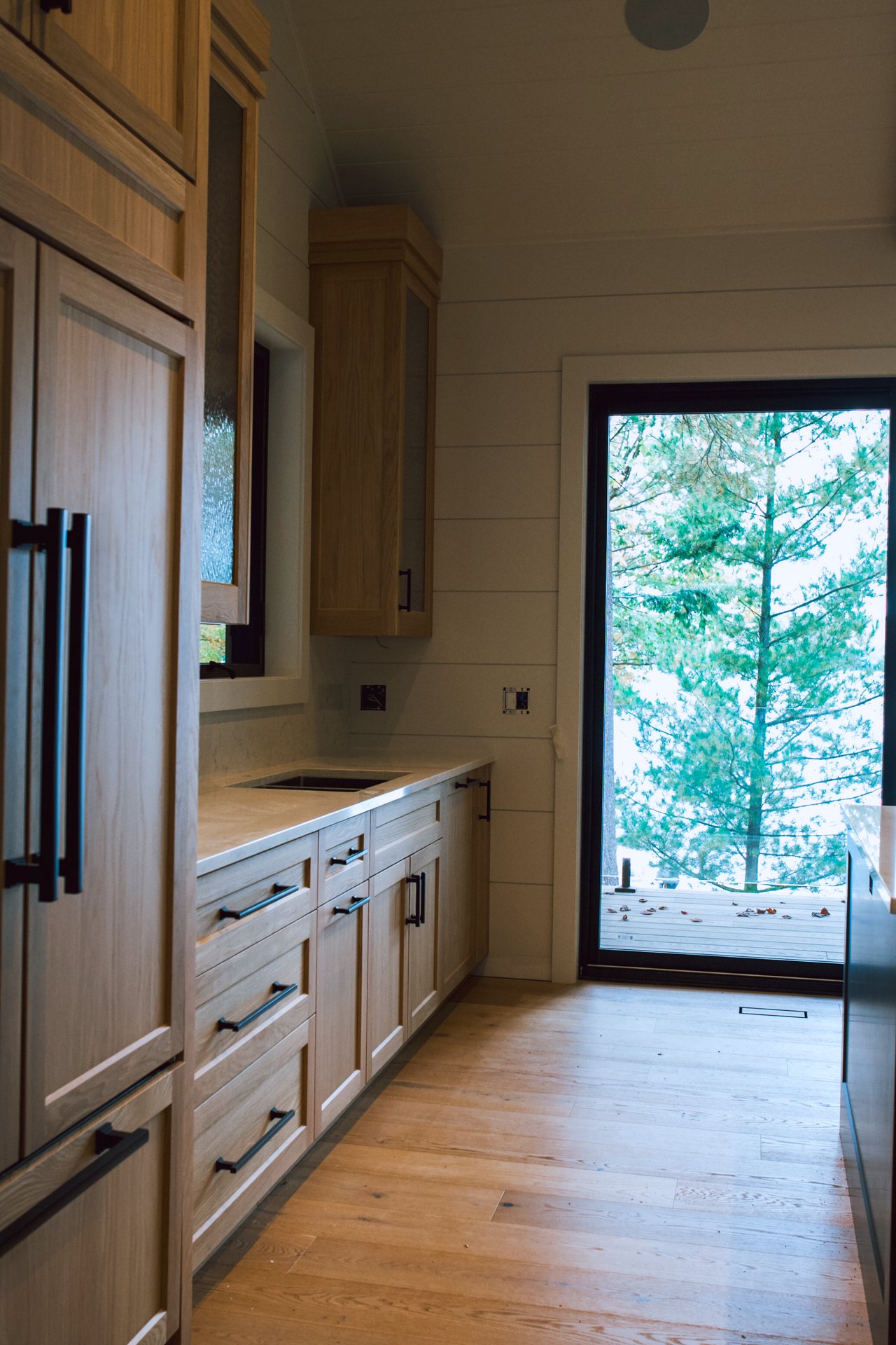 White oak kitchen run leading to a door with a view of the lake