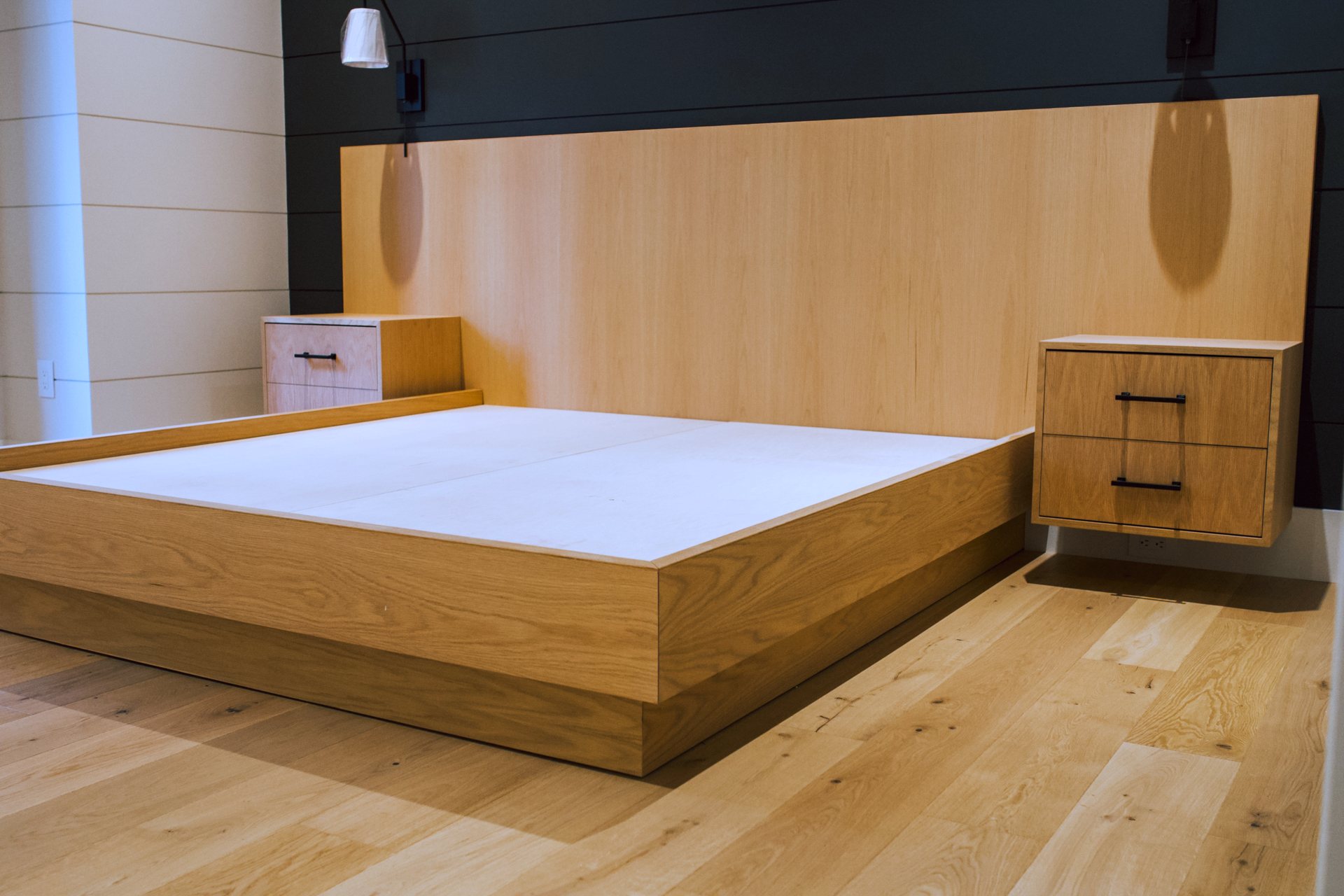 White oak platform bed with full-width headboard and floating nightstands